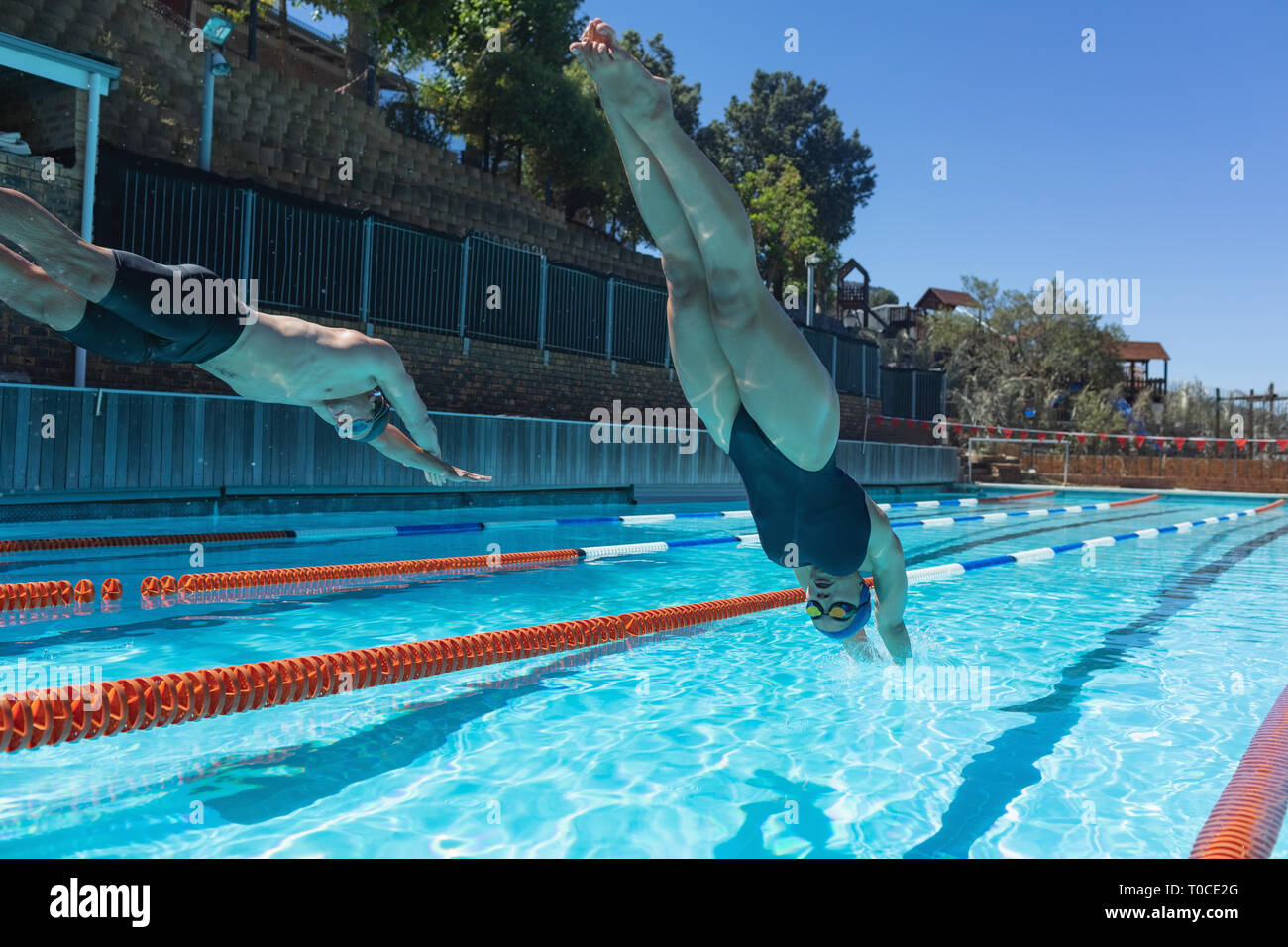 Young swimmers jumping into water at swimming pool Stock Photo