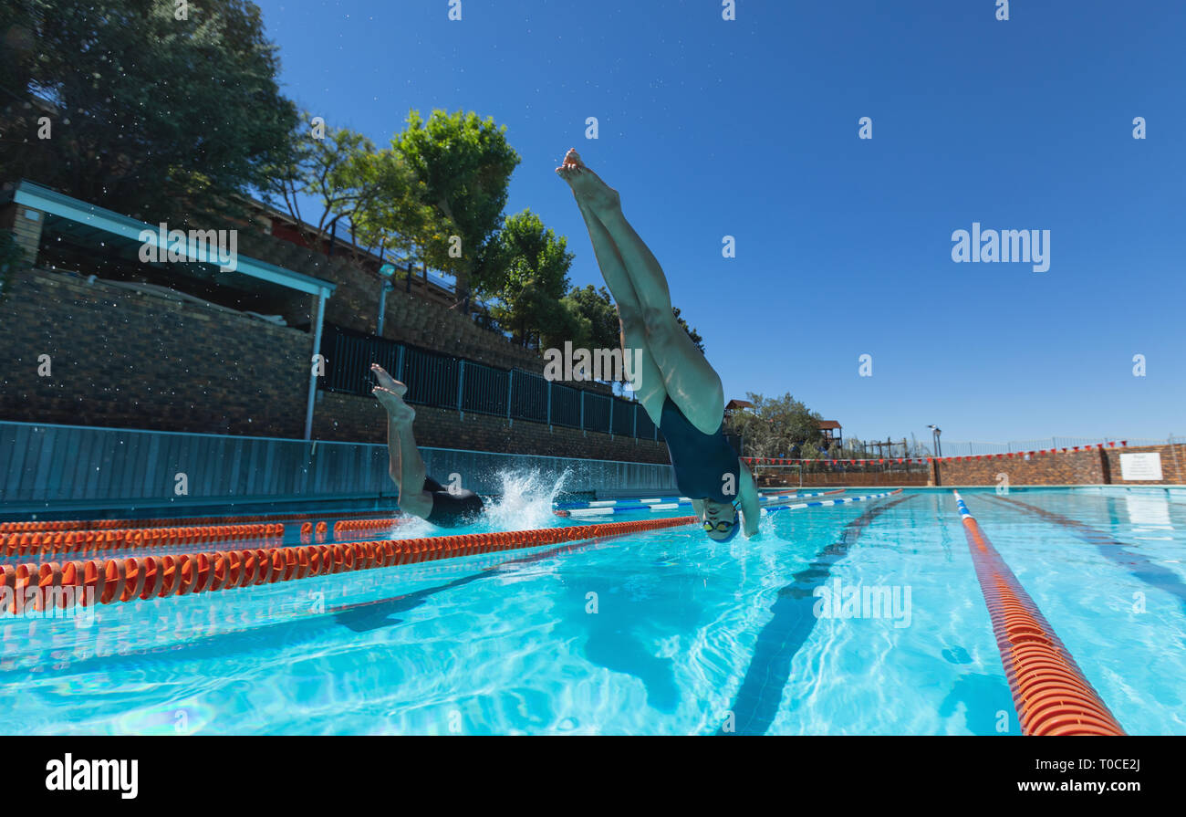 Young swimmers jumping into water at swimming pool Stock Photo