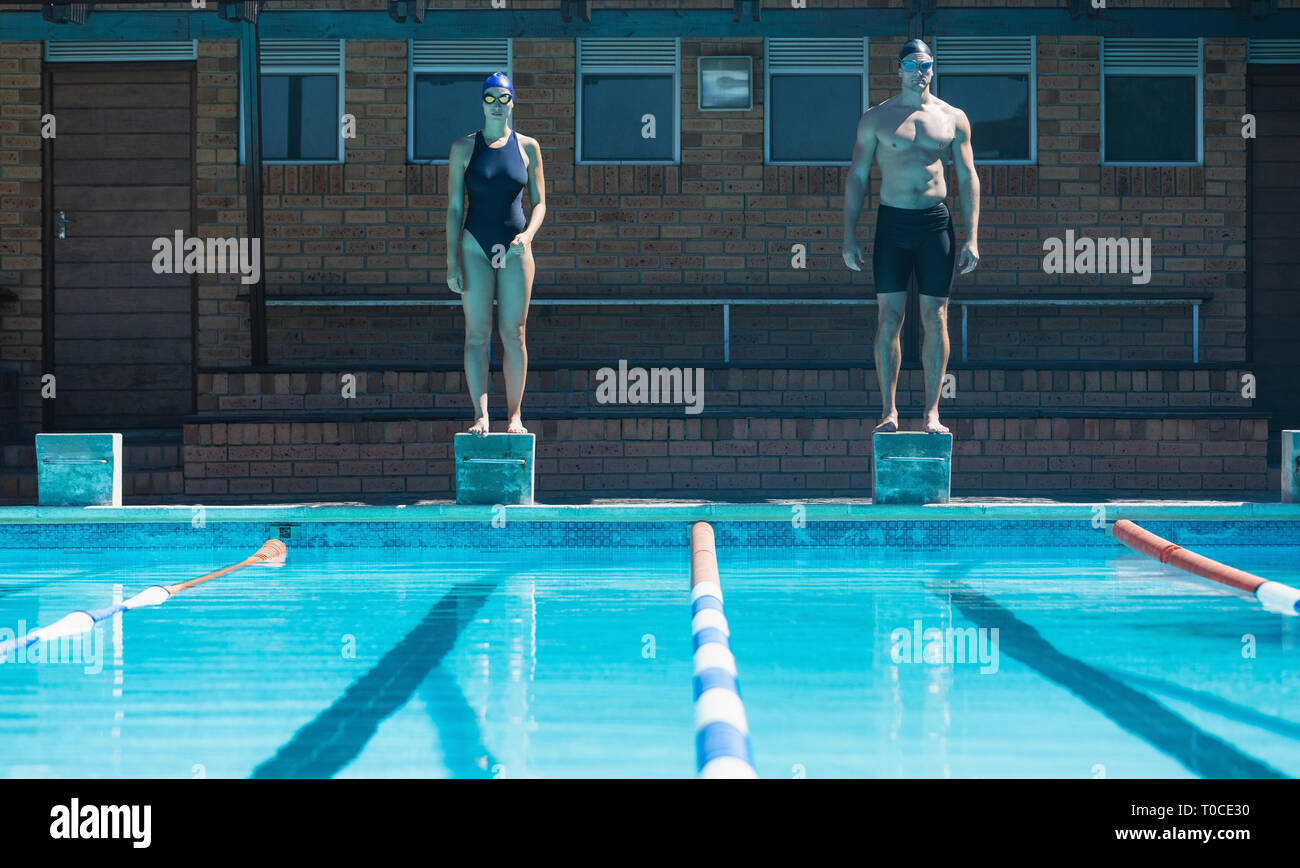 Young swimmers standing on the starting blocks at swimming pool Stock Photo