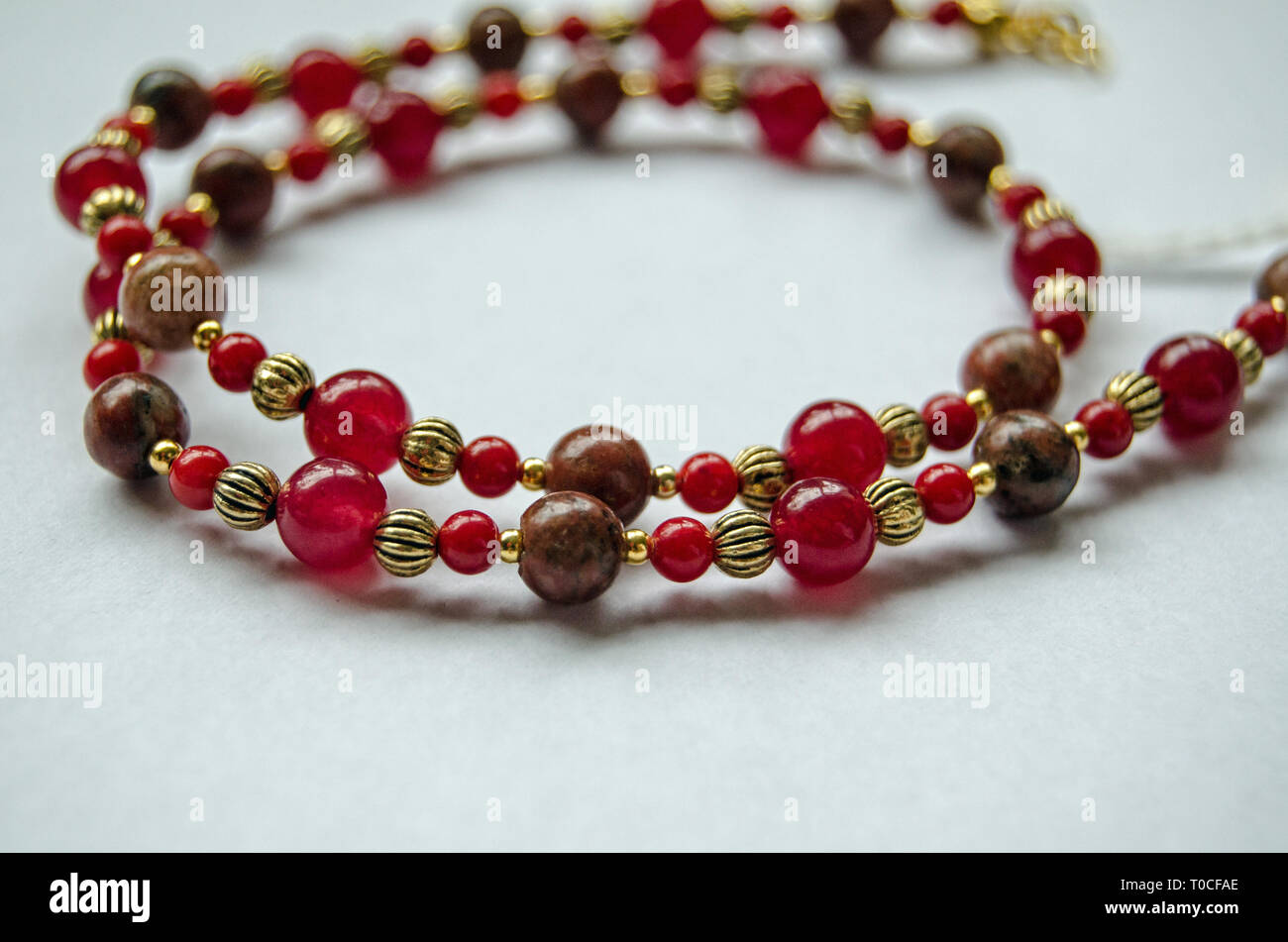 Jewellery handcrafted from jasper,coral and agate beads separated with gold plated metal beads. Stock Photo