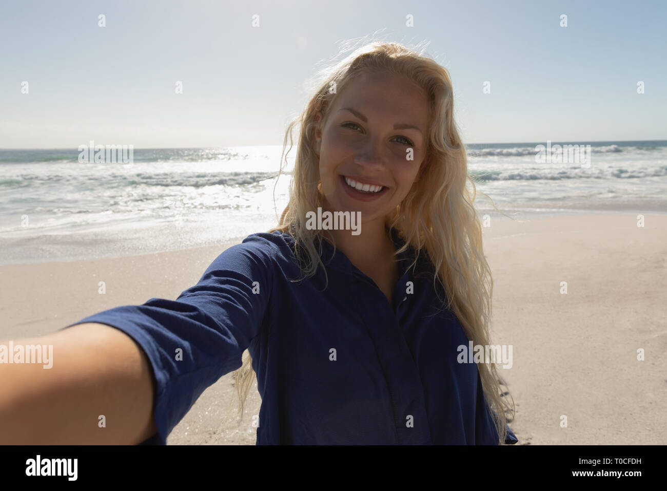 Happy eautiful Caucasian woman standing at beach on a sunny day Stock Photo