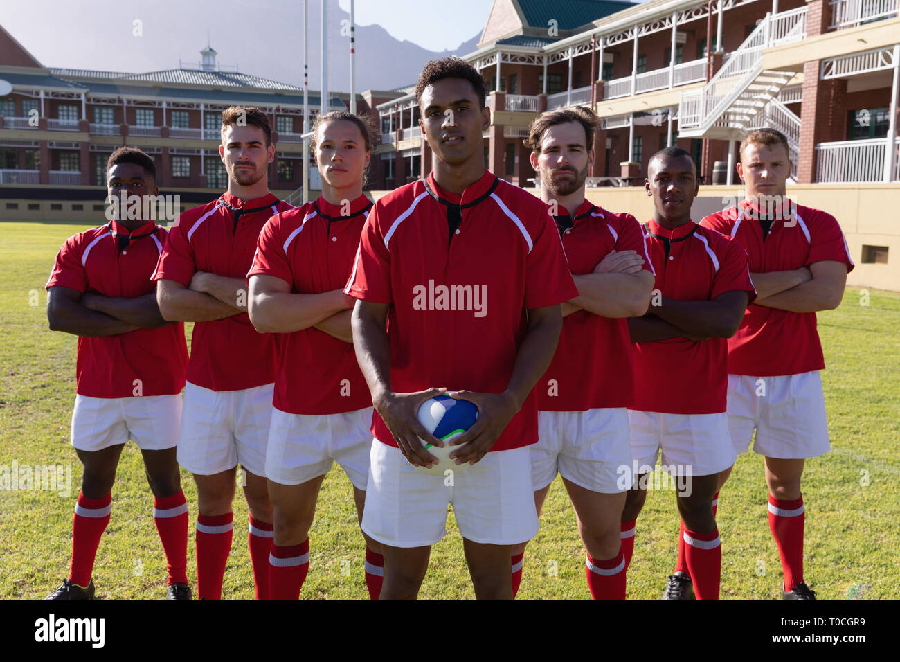 Team of male rugby players standing with rugby ball in the rugby ground ...