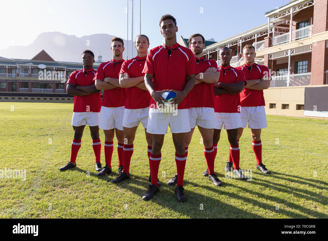 Team of male rugby players standing with rugby ball in the rugby ground