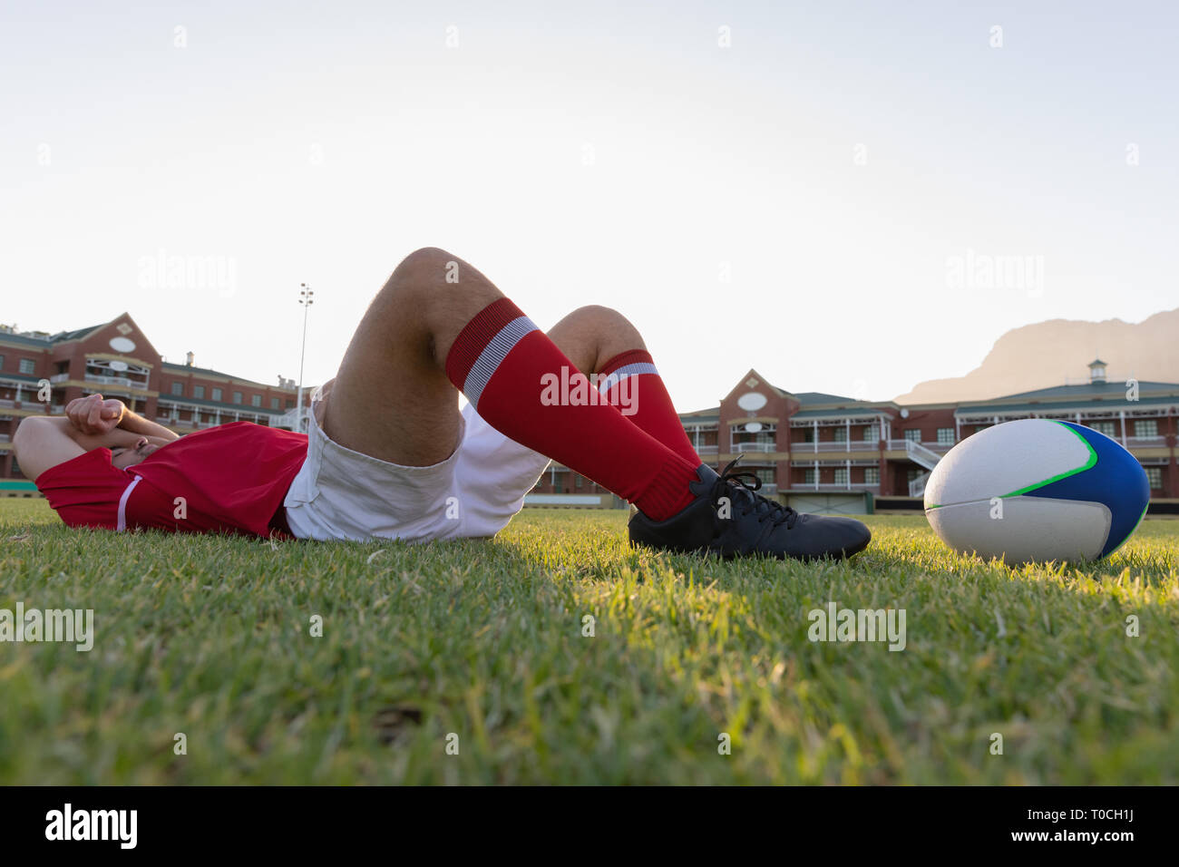Male rugby player lying with rugby ball in the ground Stock Photo - Alamy