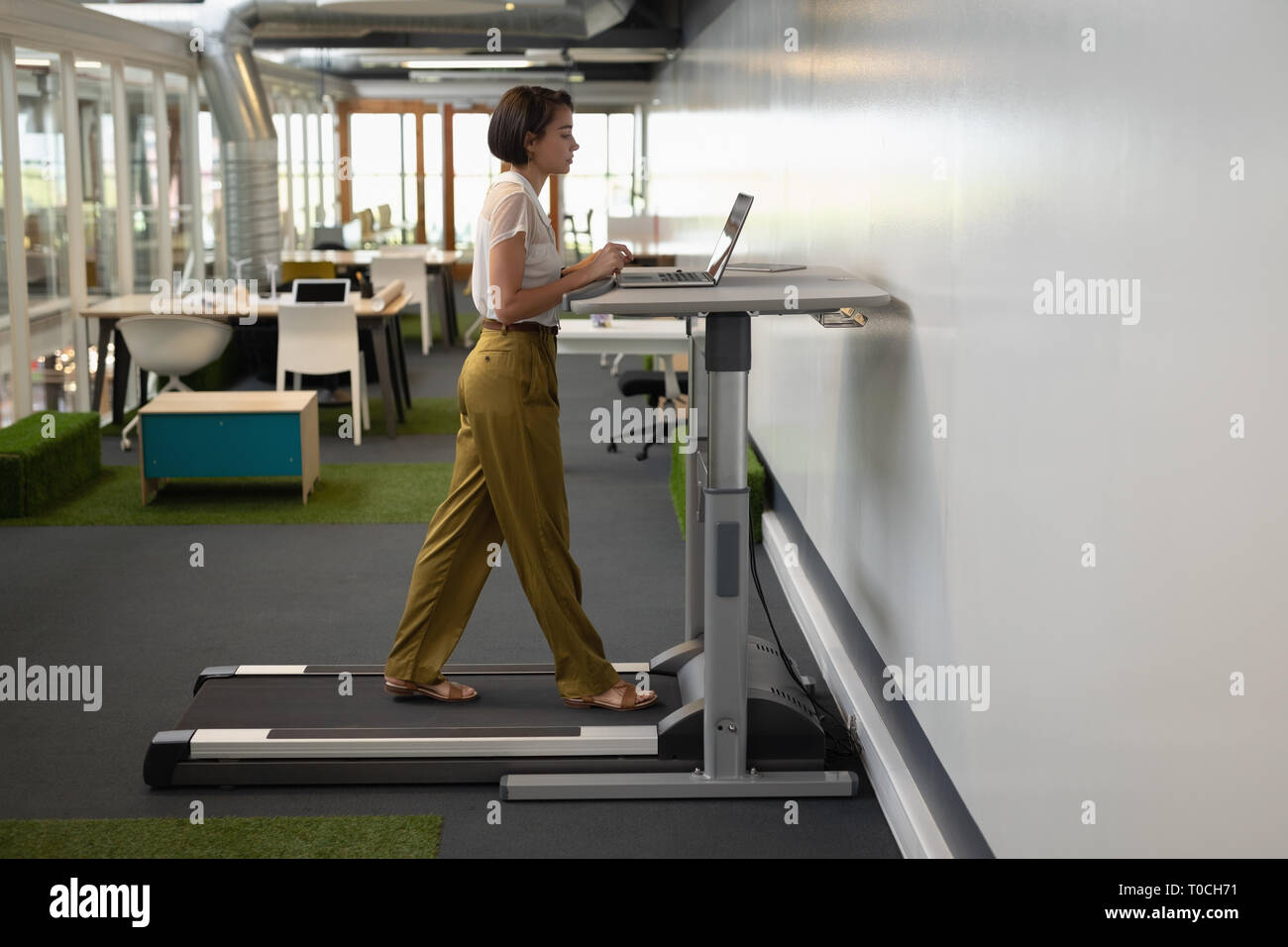 Businesswoman Working On Laptop While Doing Exercise On Treadmill