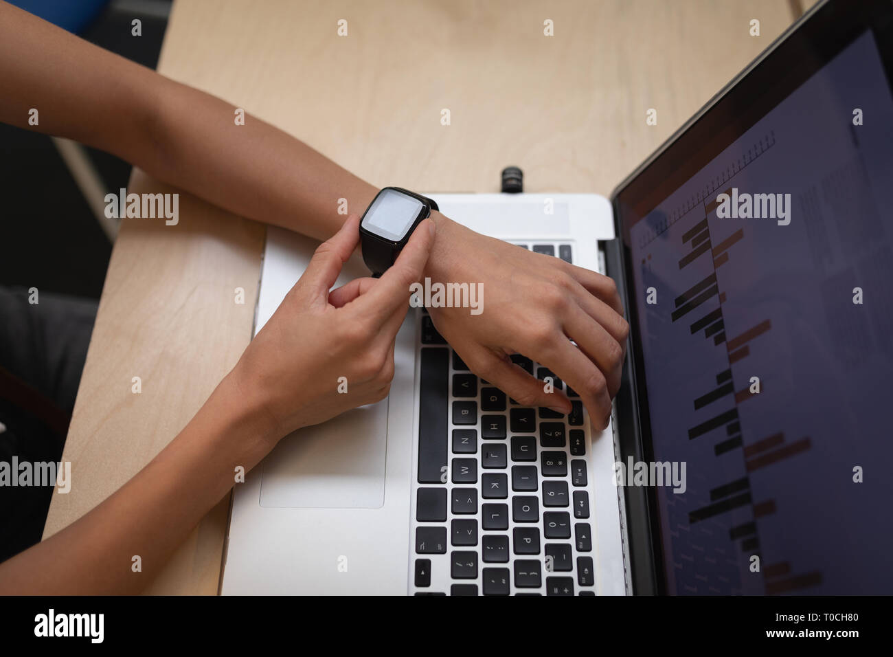 Businesswoman using smart watch at desk in office Stock Photo