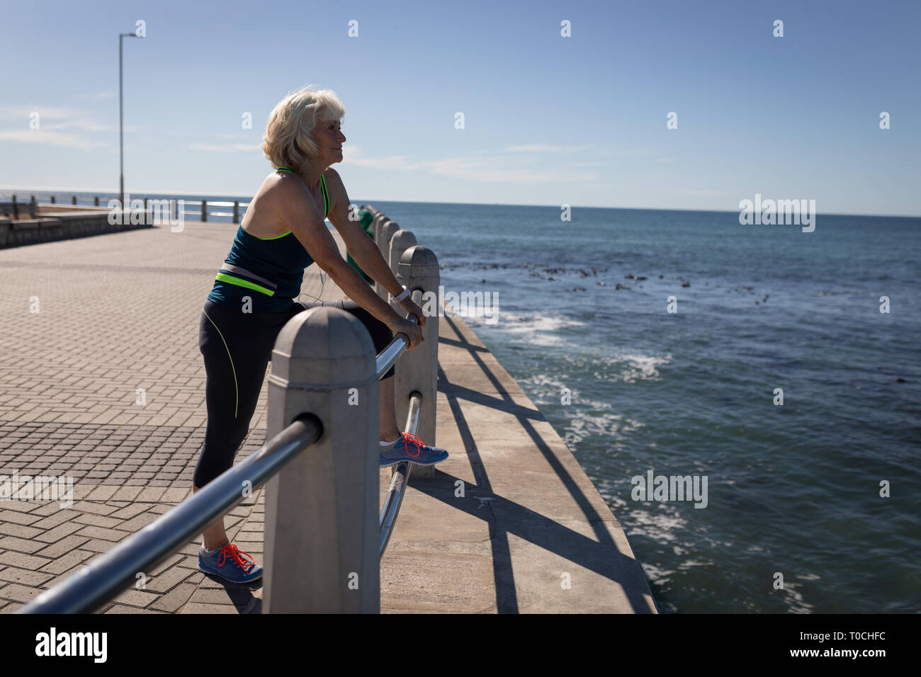 Active senior woman leaning on the guard rail of a promenade Stock Photo