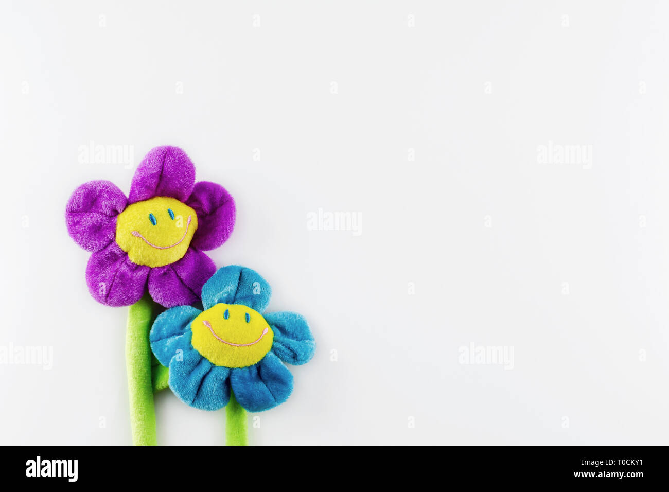 Two toy plush smiling flowers on a white background on left side.  Copy space to the right and above. Stock Photo