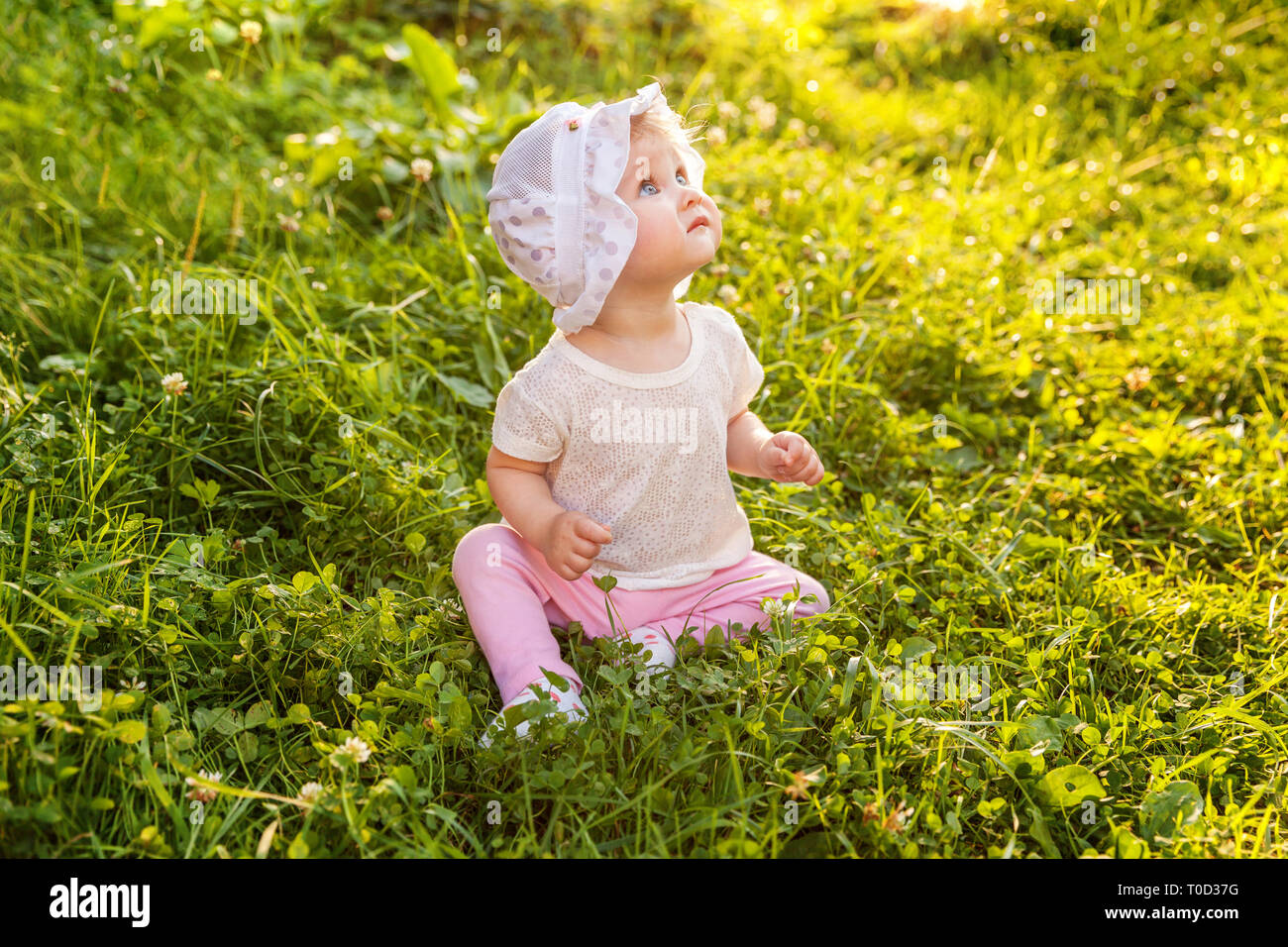Sweet happy little baby girl sitting on grass in park, garden, meadow ...