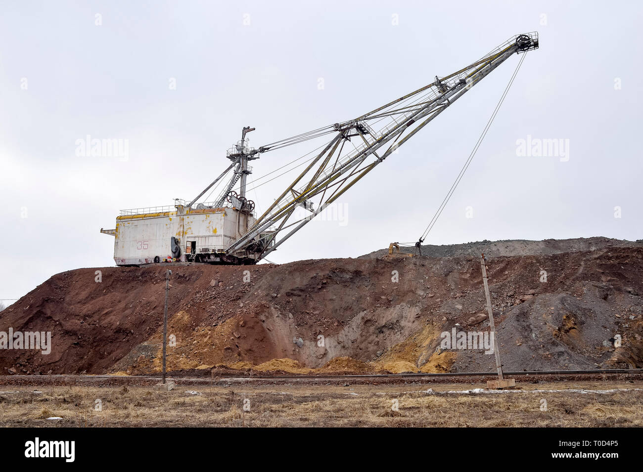 Large walking excavator in anticipation of rolling stock transporting overburden for storage in dumps. Industrial landscape after the destruction of n Stock Photo