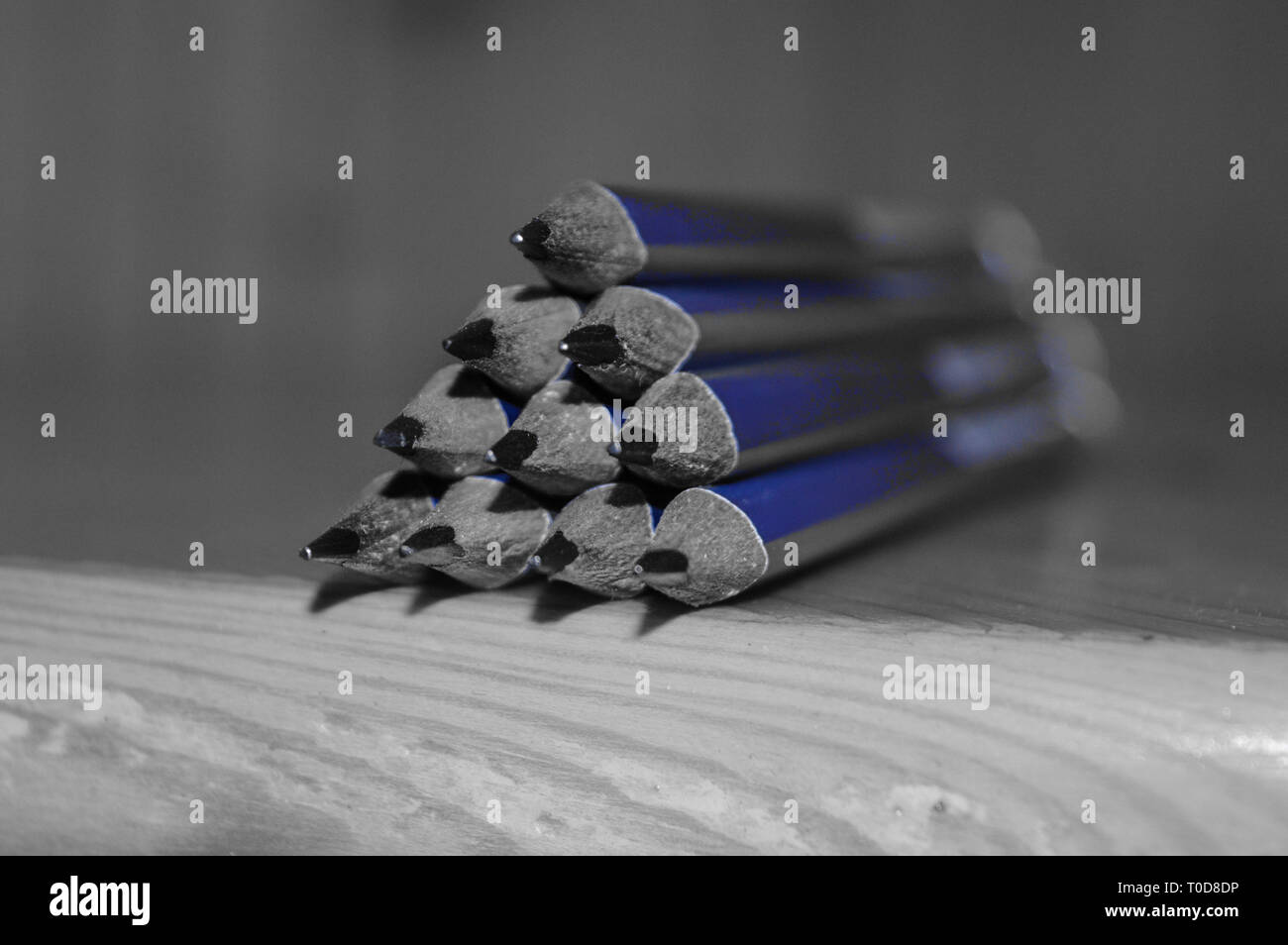 Macro shot of pencils with sharpened tips kept on a table. Black and white photo with selective blue colour Stock Photo