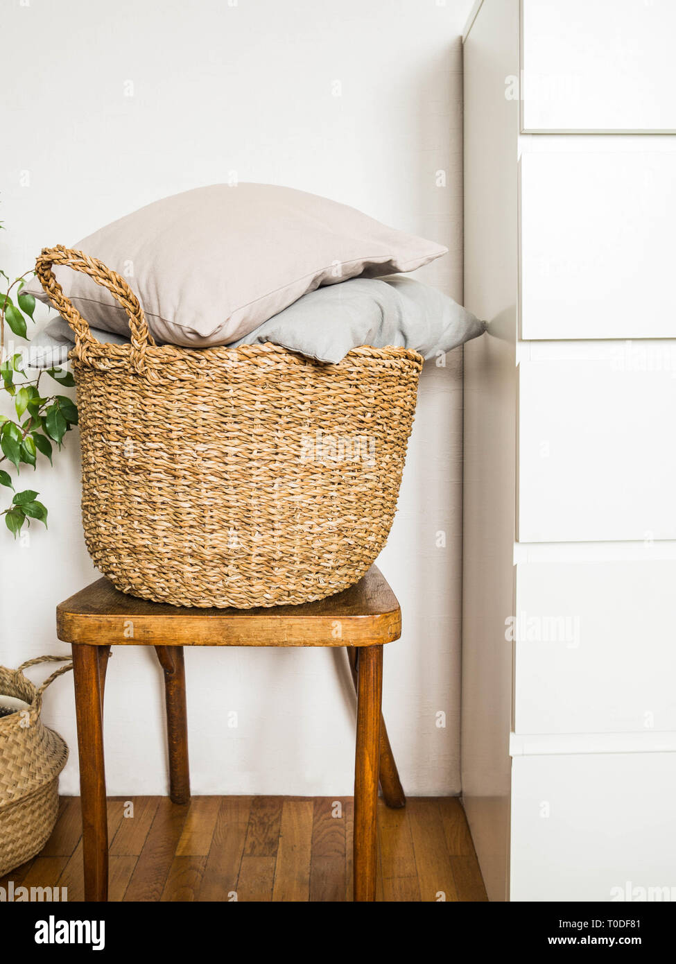 Wicker basket with gray cushions on a wooden vintage chair against a