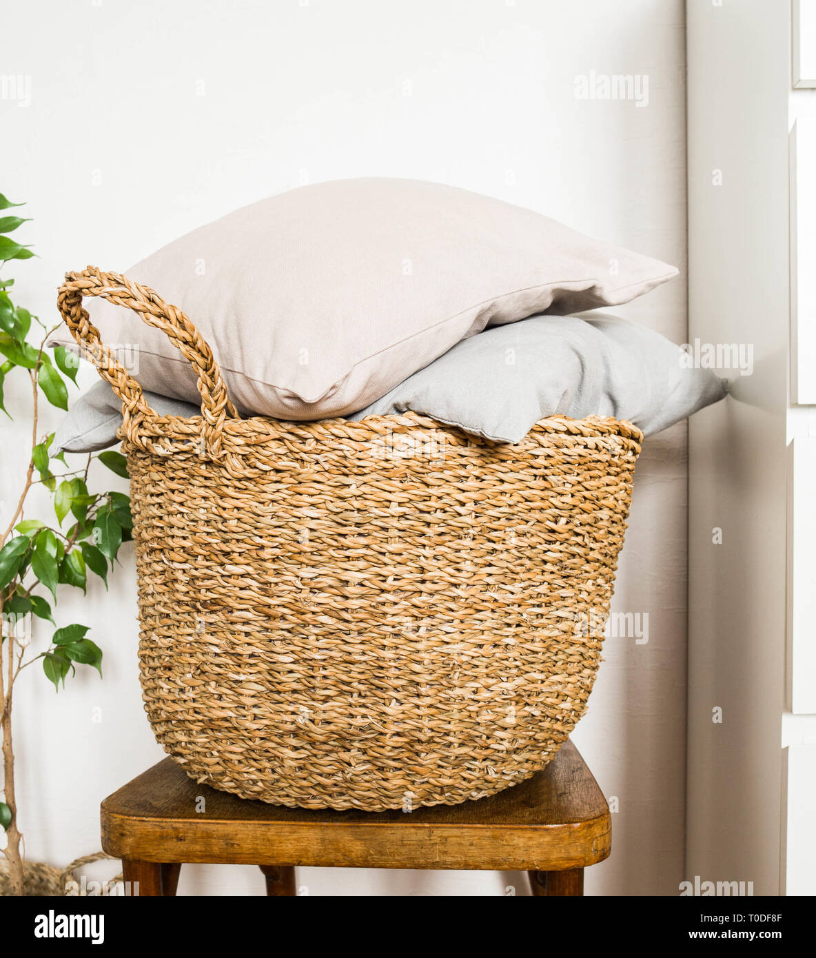 Wicker basket with gray cushions on a wooden vintage chair against a