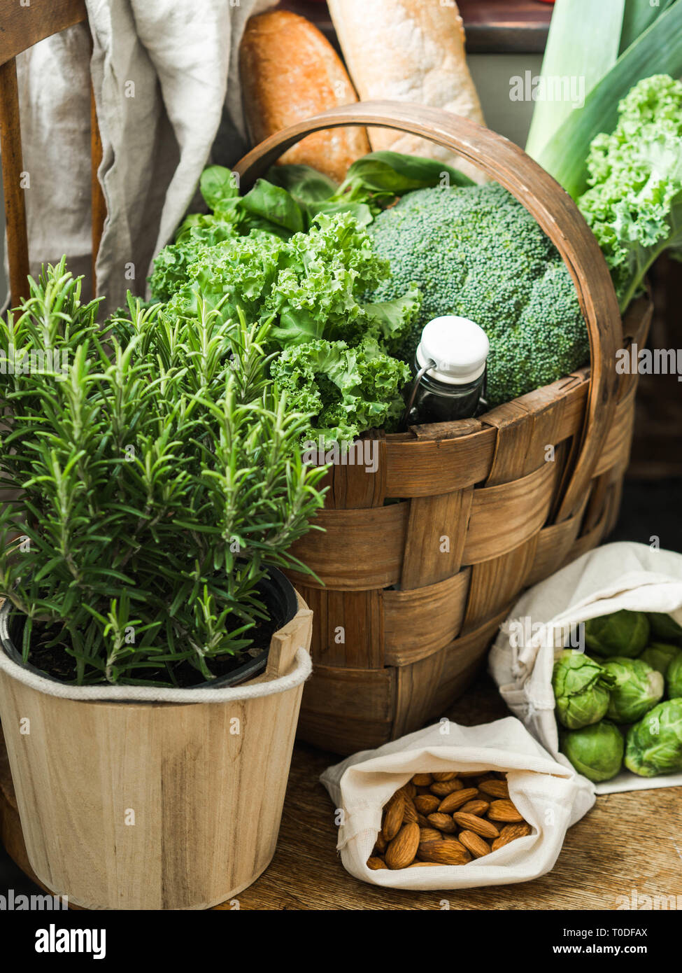 Healthy vegetarian ingredients for cooking. Various clean vegetables, herbs, nut and bread in basket on wooden chair. Products from the market without Stock Photo