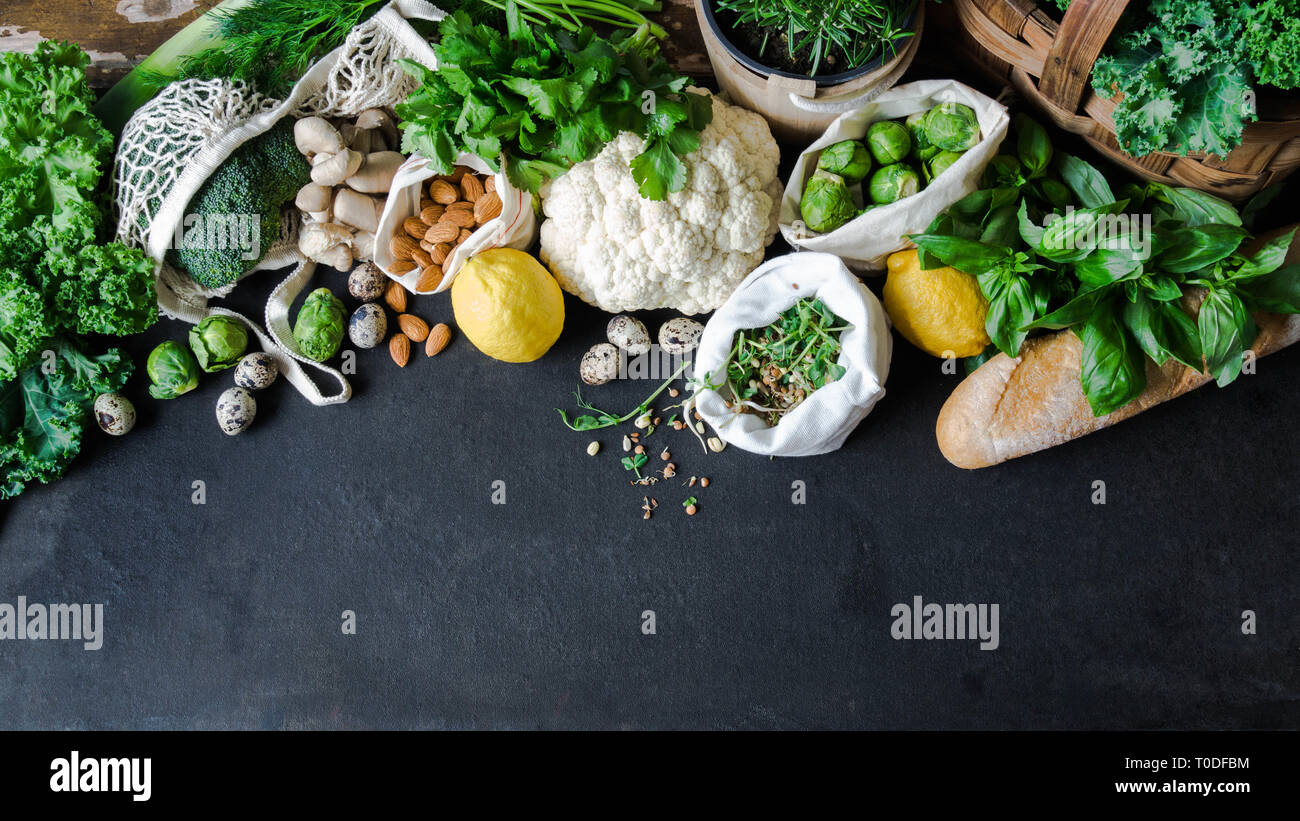 Healthy vegetarian ingredients for cooking. Various clean vegetables, herbs, nut and bread on black background. Products from the market without plast Stock Photo