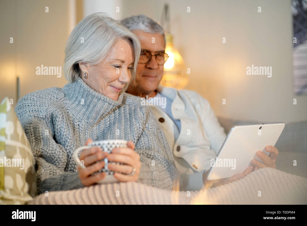 Senior couple relaxing at home on couch with tablet Stock Photo - Alamy