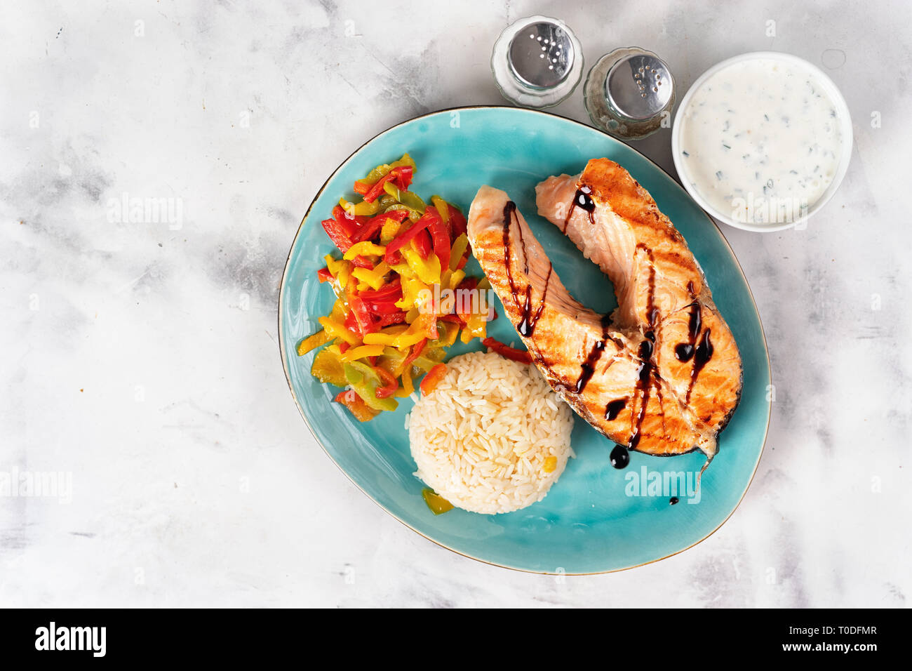 Top view of grilled salmon steak with steamed paprika and rice on white