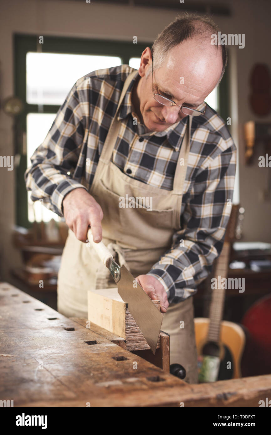 Mature carpenter using a double edged Japanese pull saw inside his workshop Stock Photo