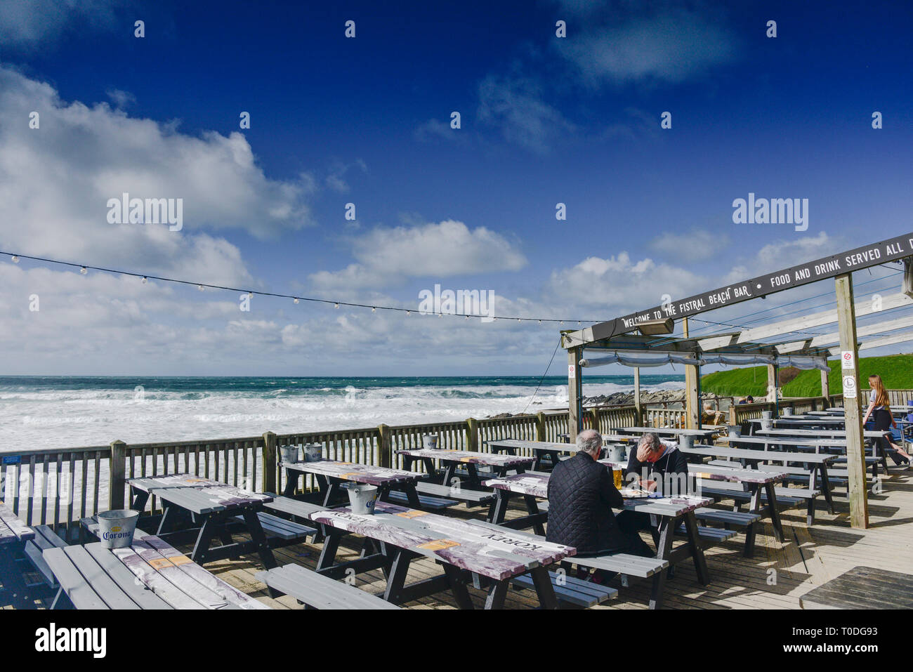 People relaxing on the outside decking area of the Fistral Beach bar in Newquay in Cornwall. Stock Photo