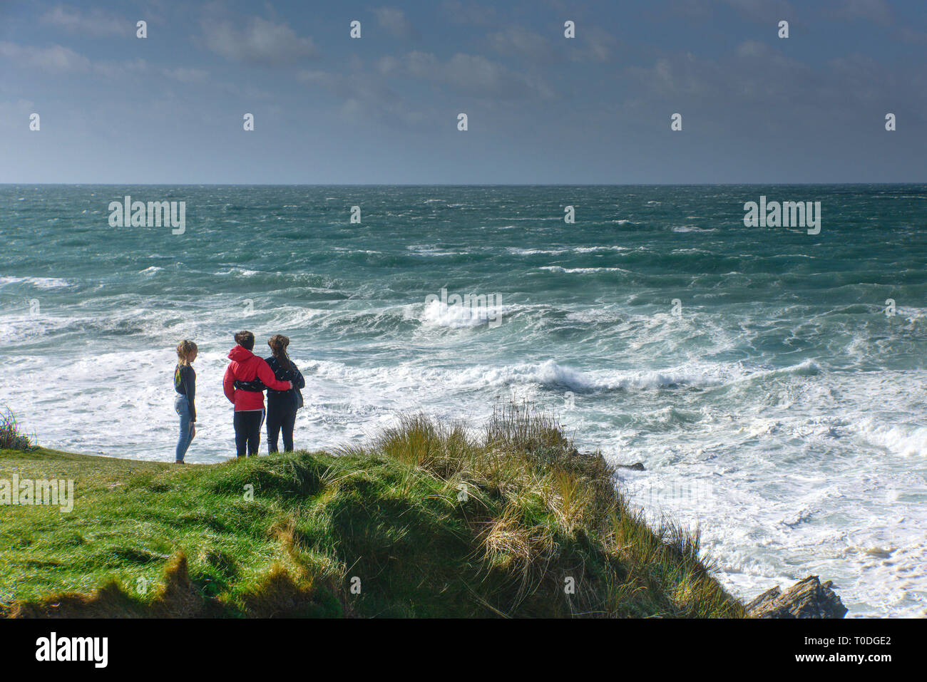 Young people looking out to sea on the rugged coastline at Little Fistral in Newquay in Cornwall. Stock Photo