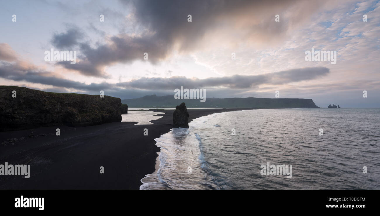 View from cape Dyrholaey on stack Arnardrangur and Reynisdrangar basalt sea stacks. Black volcanic sand on the ocean coast. Tourist attraction in the  Stock Photo