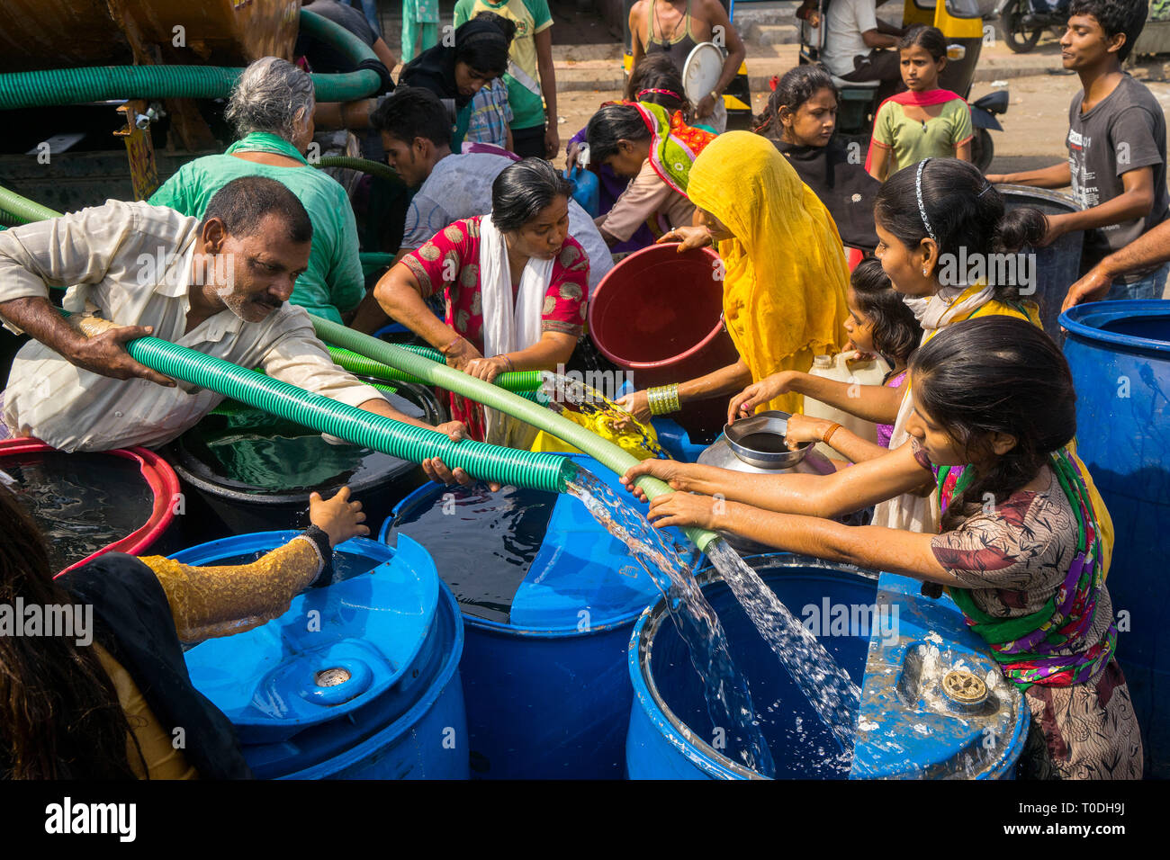 People filling water in plastic drums from water tanker, Bhiwandi, Maharashtra, India Stock Photo