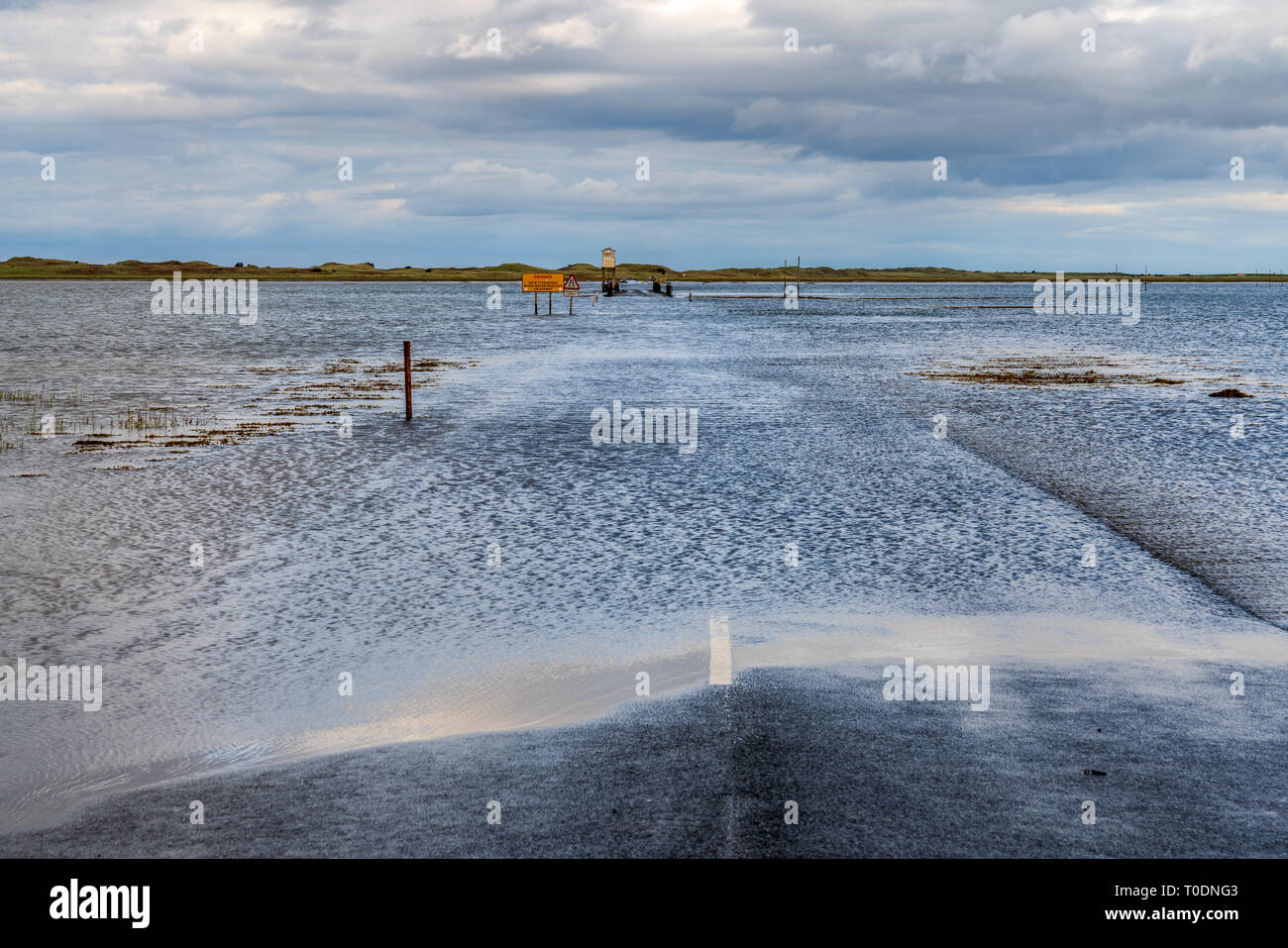 Near Beal, Northumberland, England, UK - September 08, 2018: Flooded Road to the Holy Island of Lindisfarne with a car waiting Stock Photo