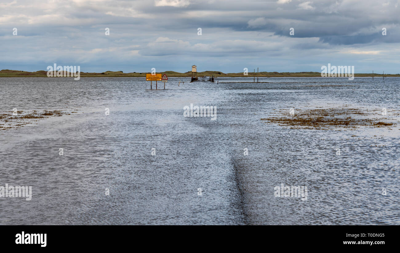 Near Beal, Northumberland, England, UK - September 08, 2018: Flooded Road to the Holy Island of Lindisfarne with a car waiting Stock Photo