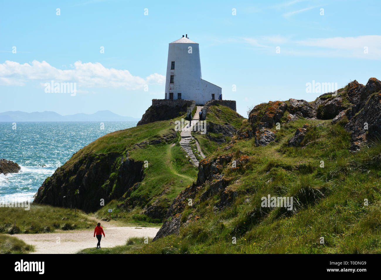 Walking towards the iconic Twr Mawr lighthouse on Llanddwyn Island which is situated of the coast of Anglesey in North Wales. Stock Photo