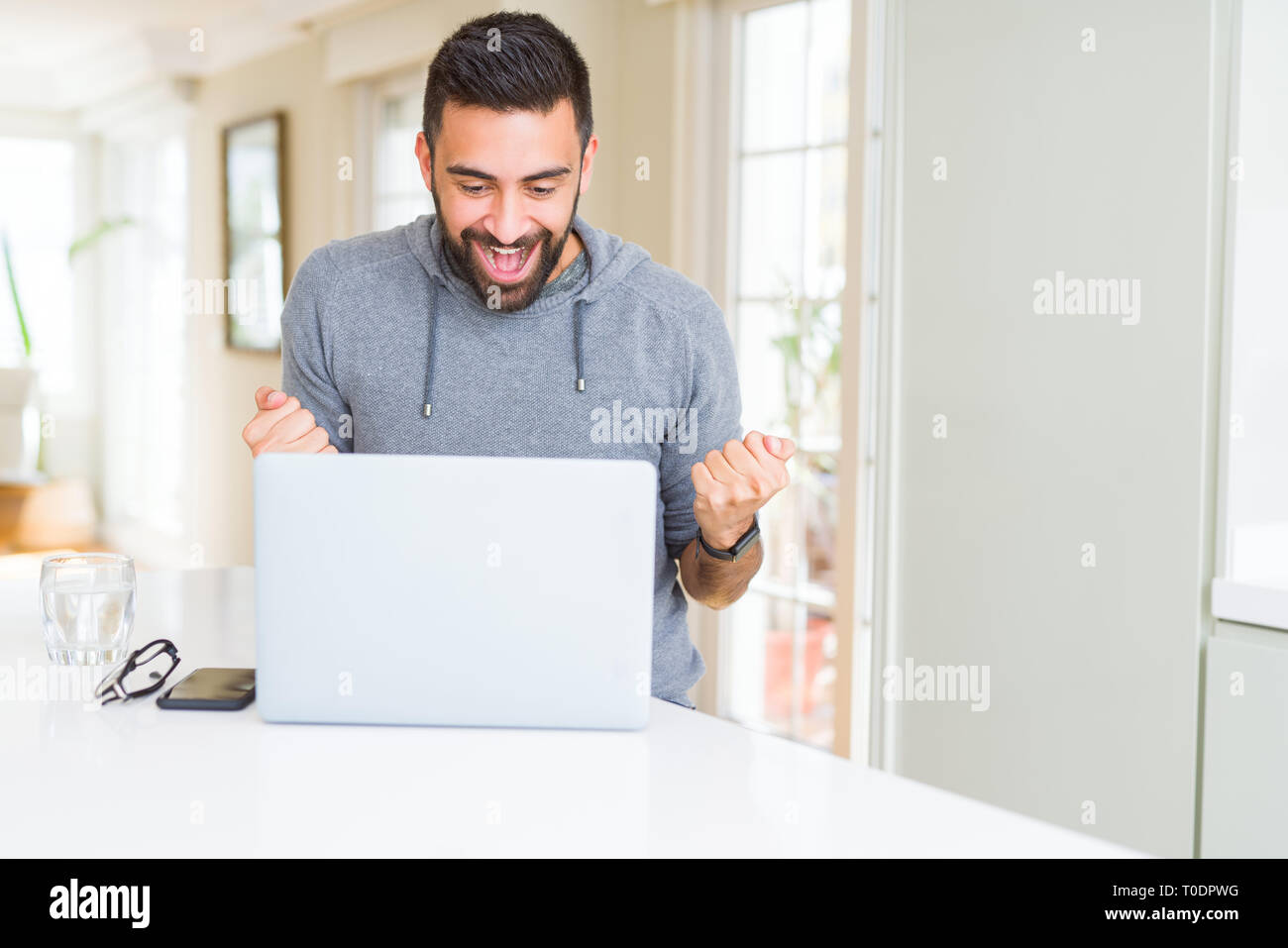 Hispanic Man Using Computer Handsome hispanic man working using computer laptop screaming proud and ...