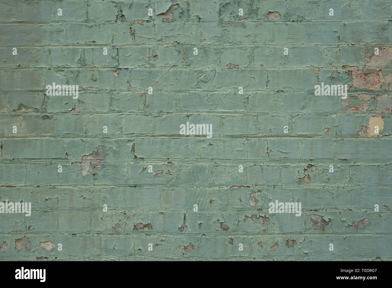 A flaking paint on a teal brick wall, ideal for backgrounds and copy