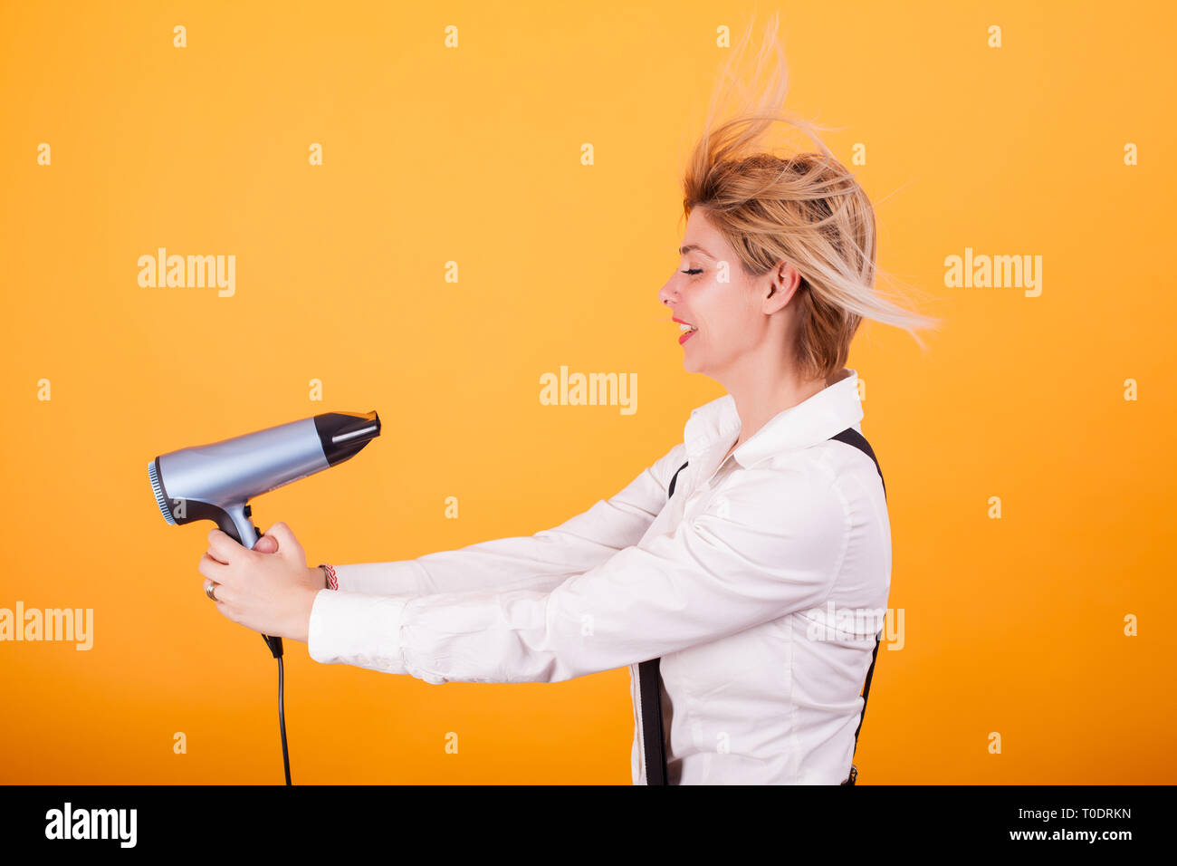 Young Funny Woman Blowing Her Short Hair With A Hair Drayer Over