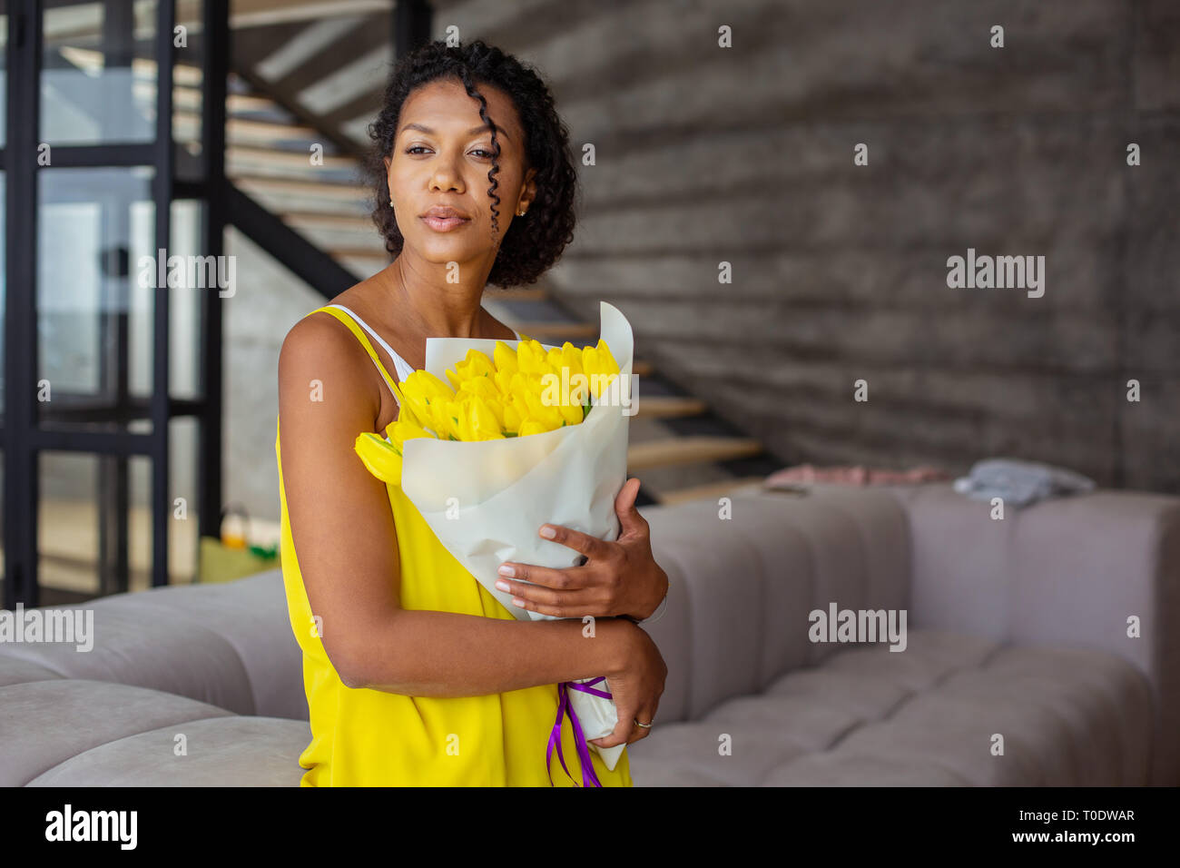 Attractive international female person embracing her flowers Stock Photo