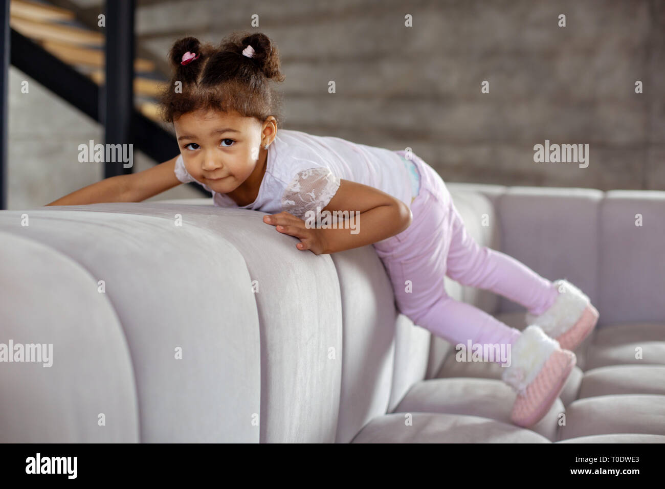 Concentrated darkskinned child climbing on to sofa Stock Photo Alamy