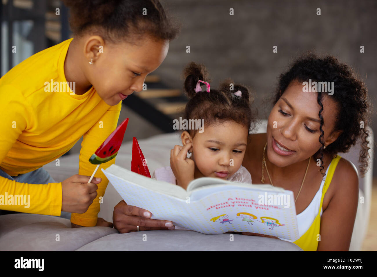 Positive delighted children reading book with mom Stock Photo - Alamy