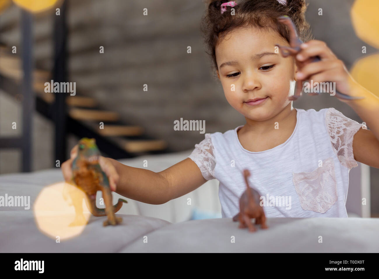 Pleased curly-haired child looking at her toys Stock Photo