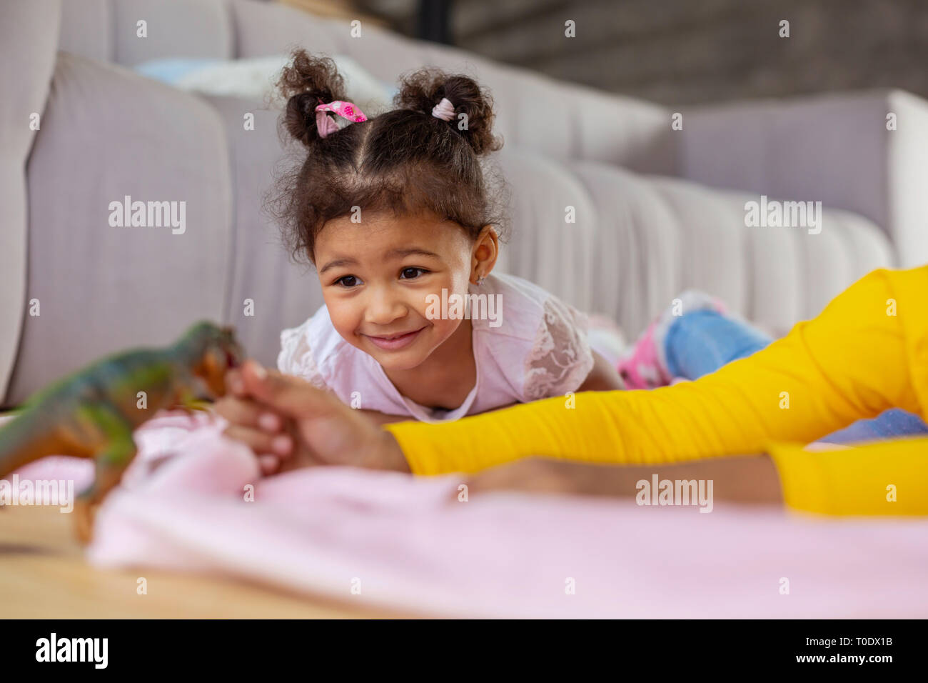 Positive delighted little girl looking at dinosaur Stock Photo