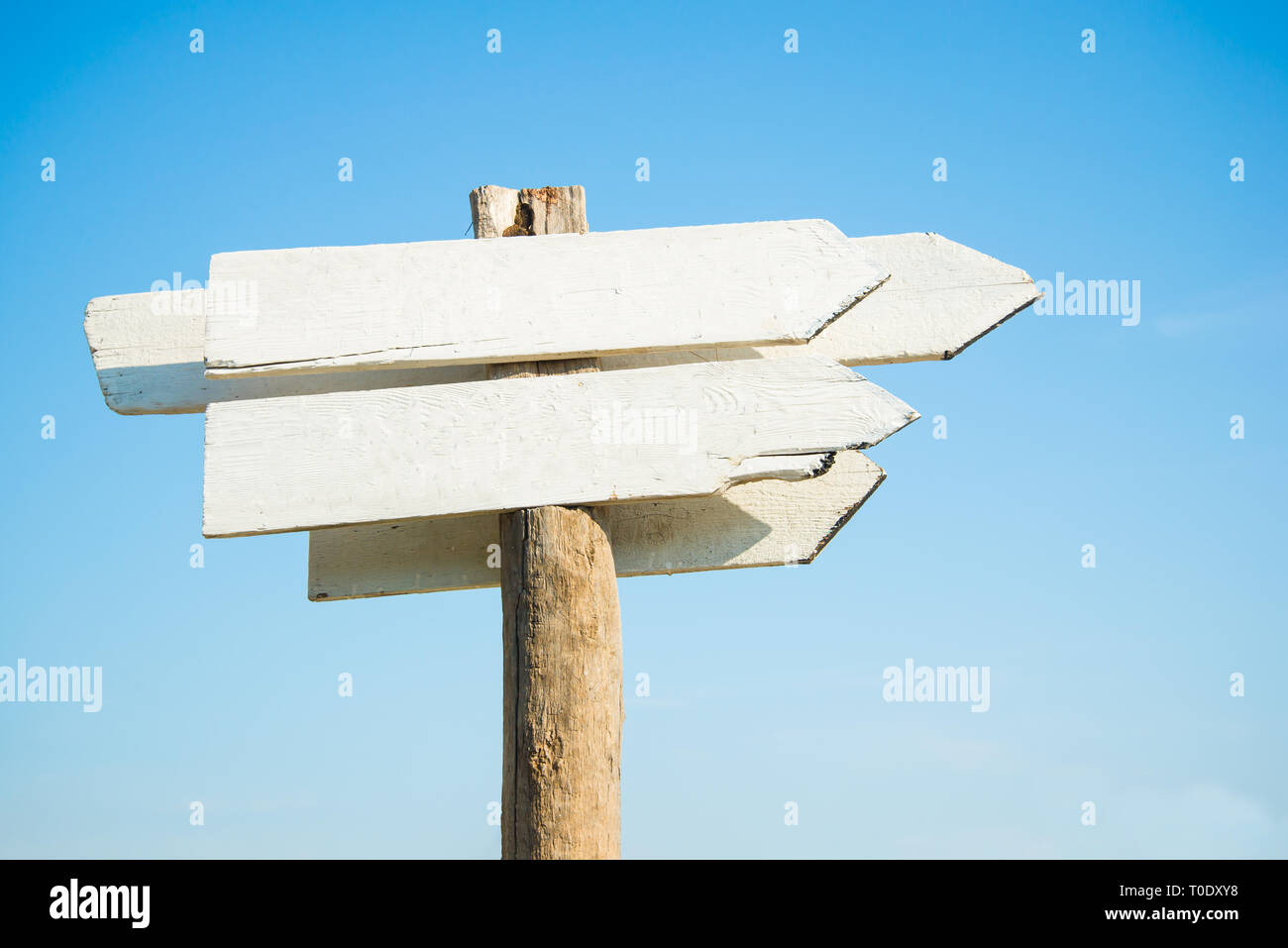 empty white wooden sign board against clear blue sky on sunny day by coast Stock Photo