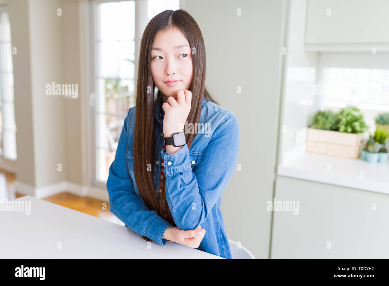 Beautiful Asian woman wearing denim jacket on white table with hand on ...