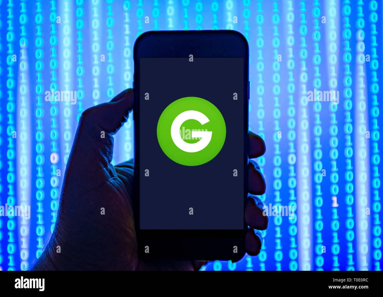 Person holding smart phone with Groupon logo displayed on the screen. Stock Photo