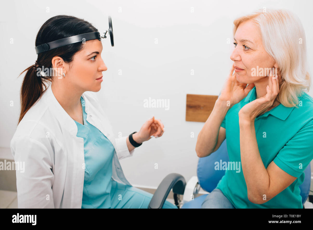 Mature patients showing pain at Throat to her otolaryngologist. Medical exam Throat and consultation. Stock Photo