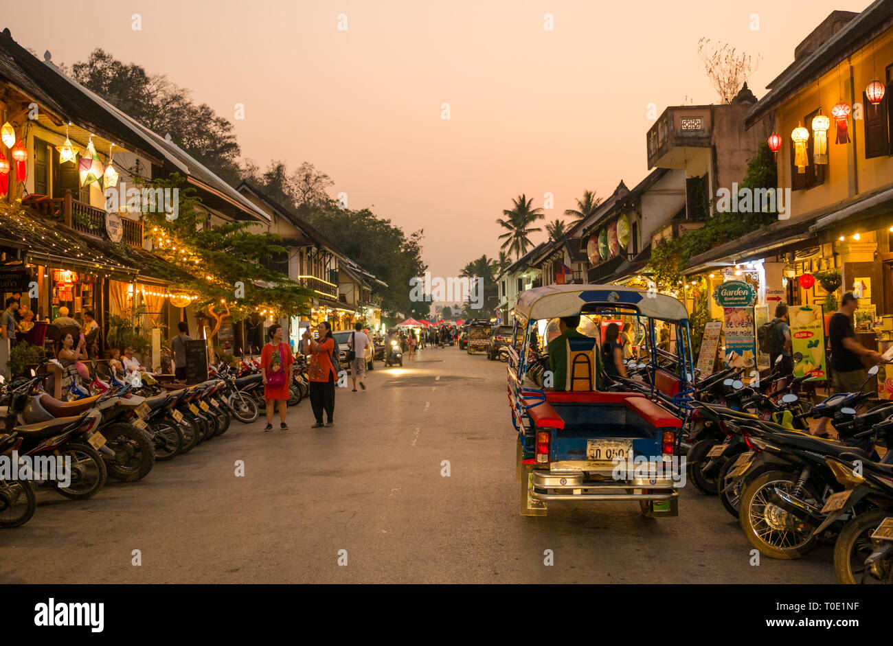 Tourists shopping at shops open at night with motorbikes and tuk tuk, Luang Prabang, Laos, SE Asia Stock Photo