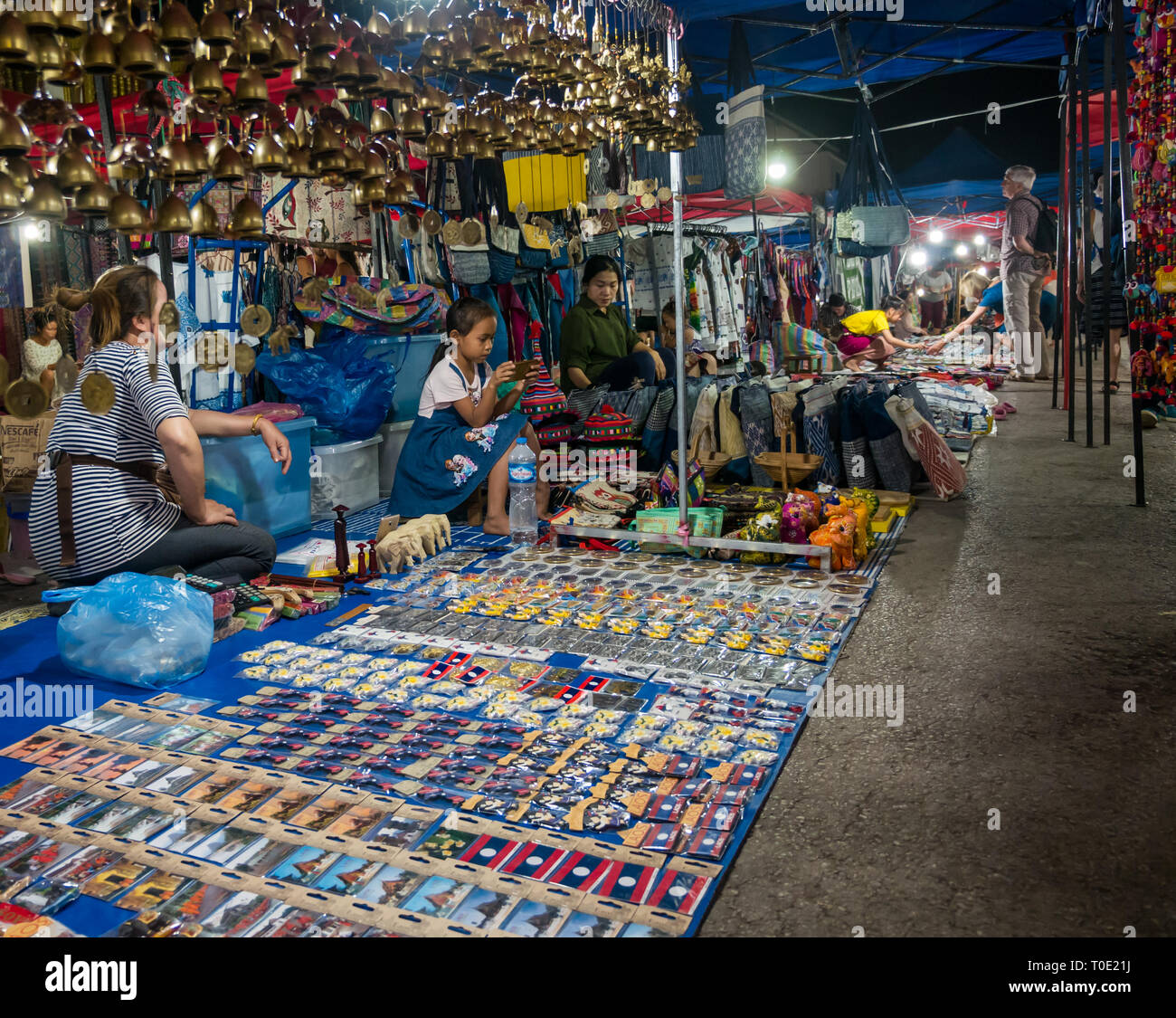 Tourist souvenirs for sale at night market with stall holders, Luang Prabang, Laos, SE Asia Stock Photo