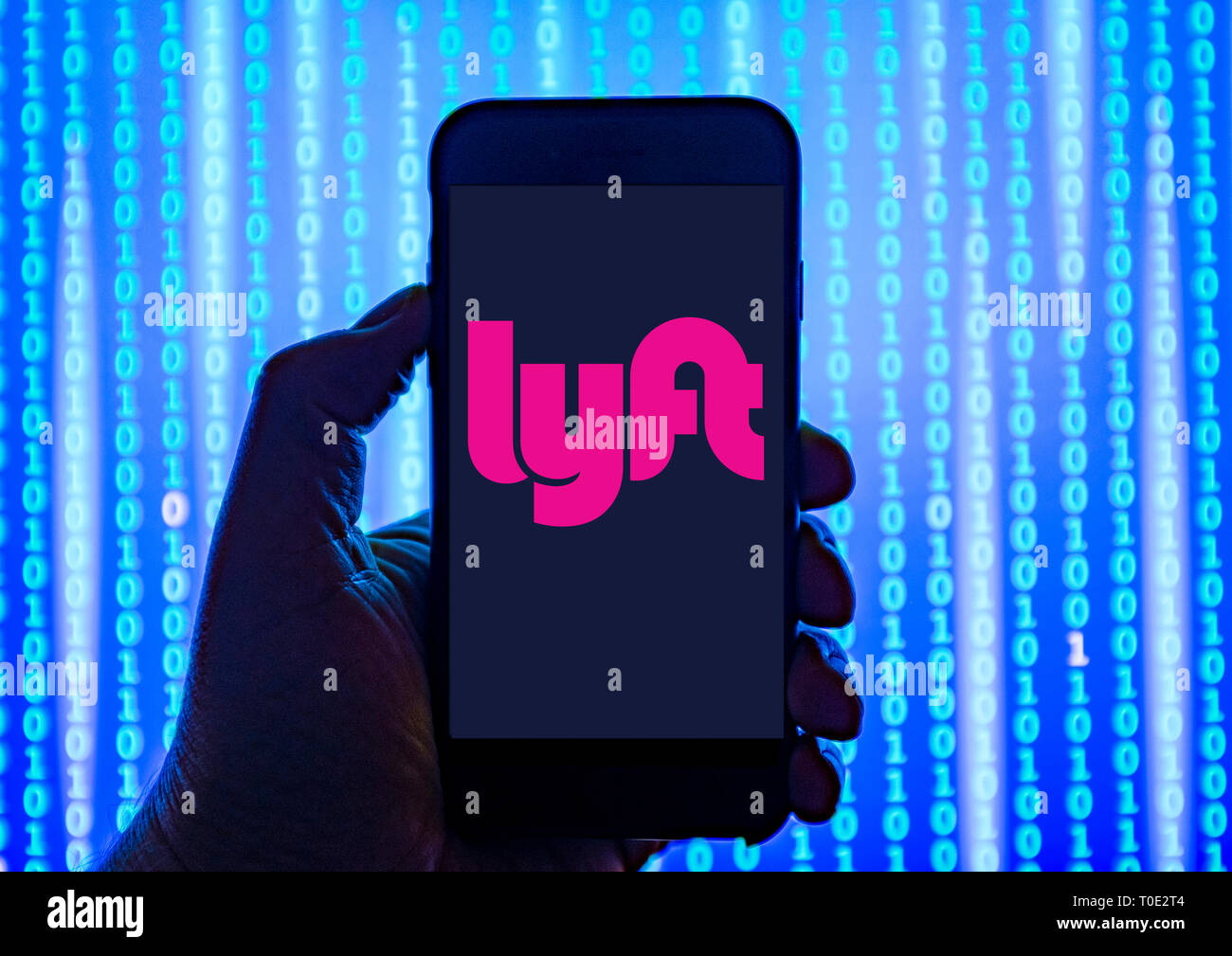 Person holding smart phone with Lyft taxi service logo displayed on the screen. Stock Photo