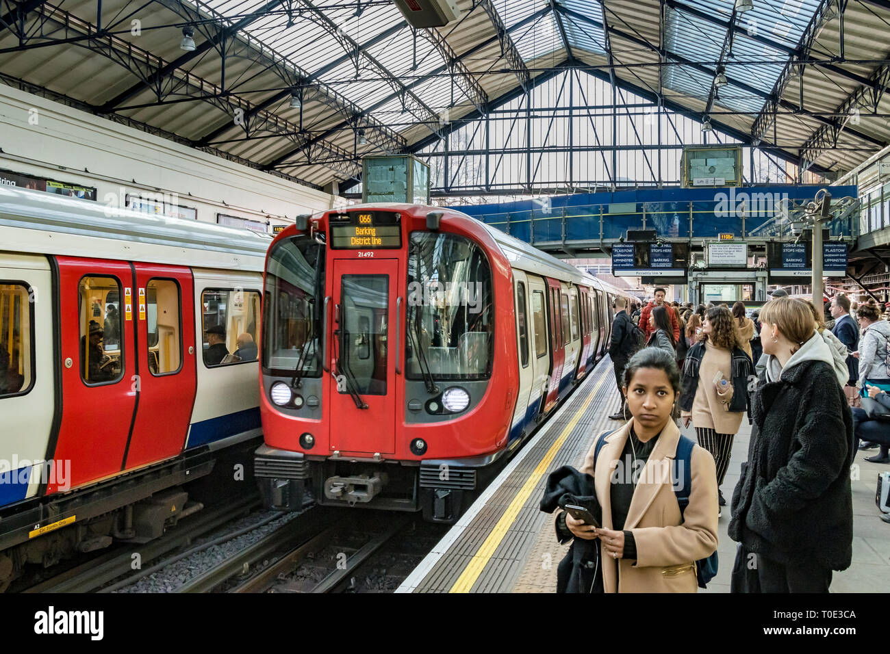 People waiting on the platform as a District Line train pulls into Earls Court Underground Station, London, UK Stock Photo