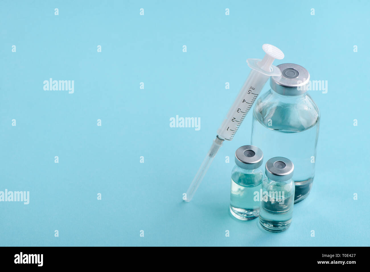 Bottle, vials and syringe on blue background with copy space. Medical ...