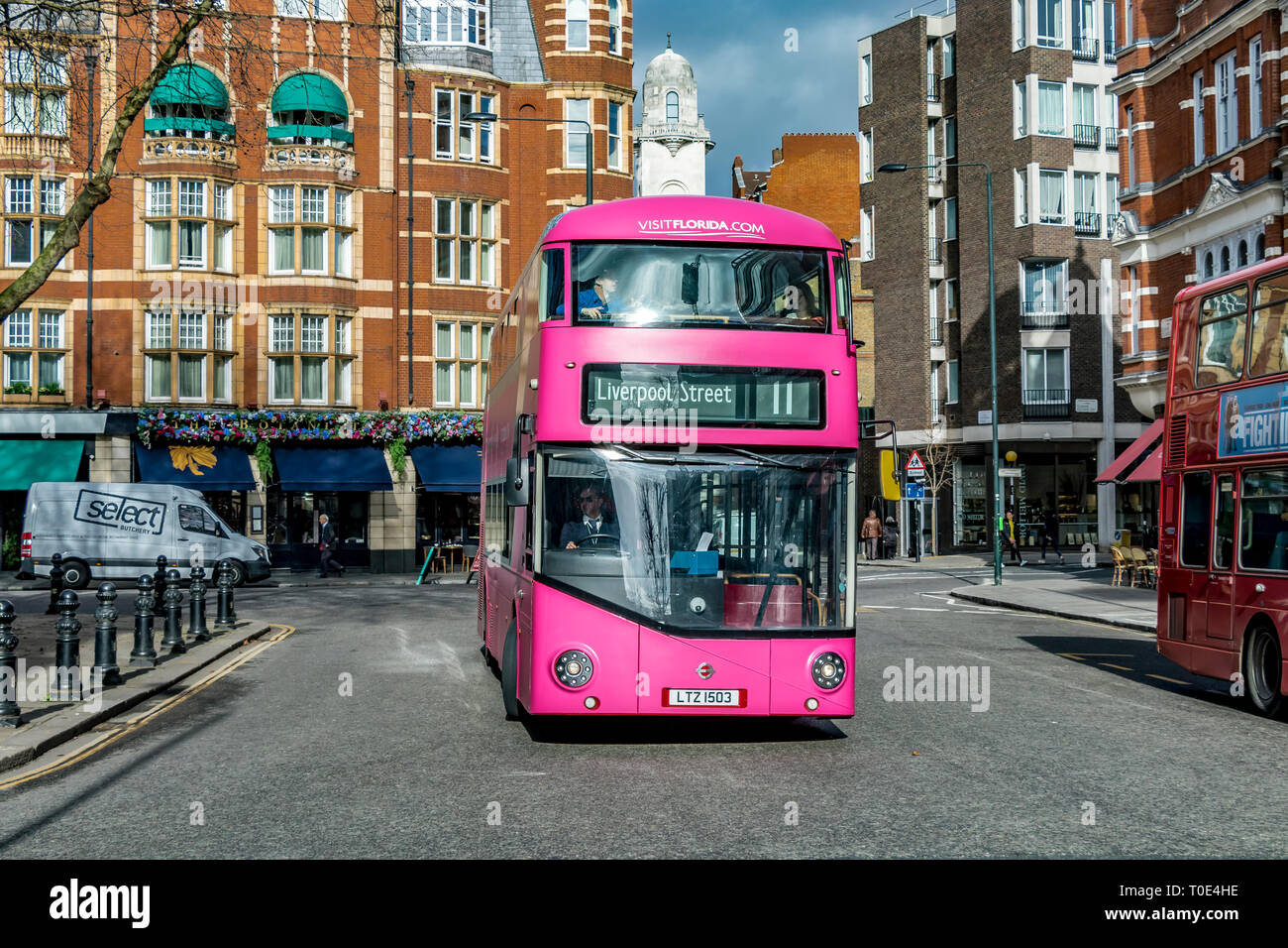 A number 11 London Bus painted pink as part of a Visit Florida advertising campaign , makes it's way around Sloane Square , London, UK Stock Photo