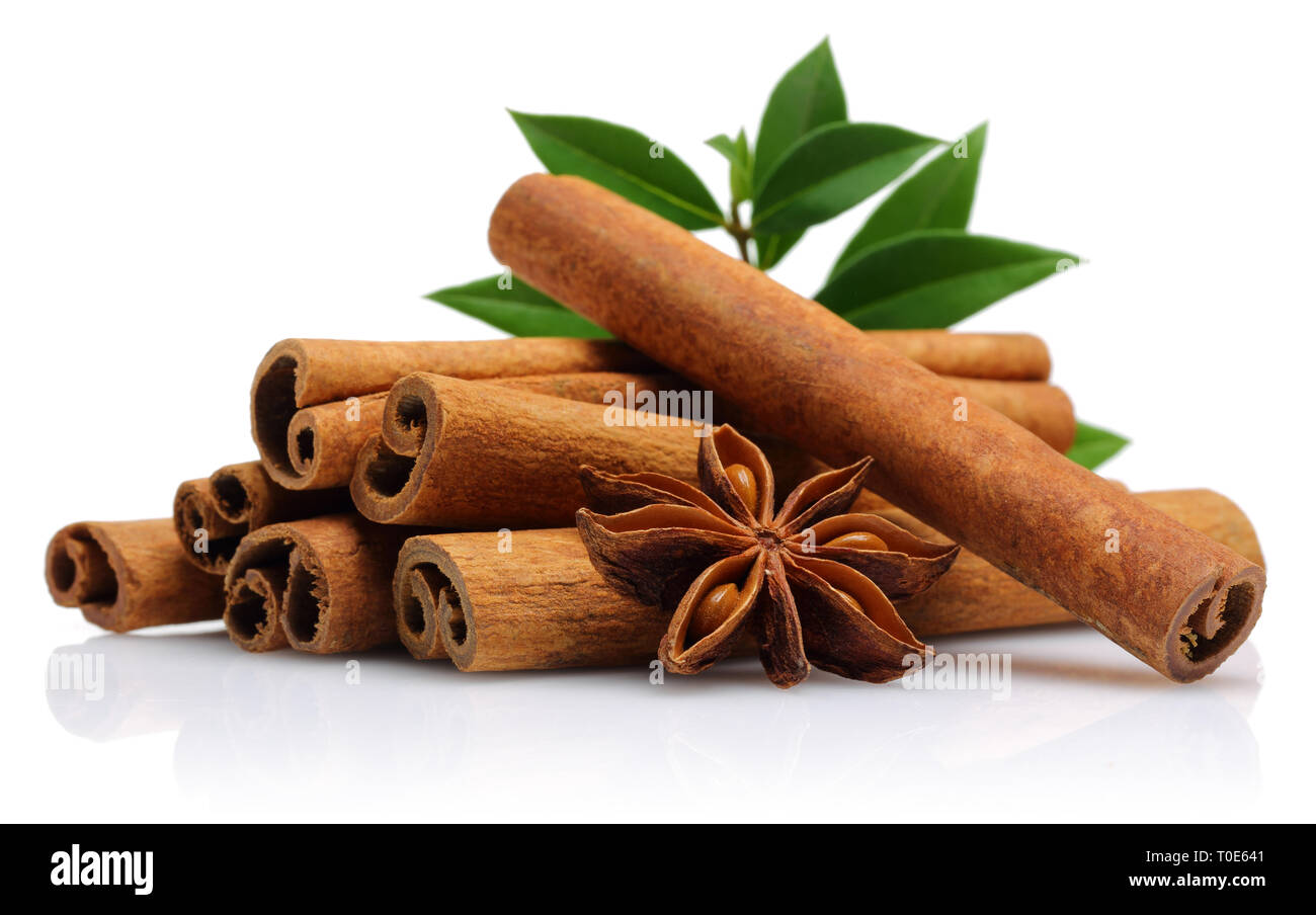 Cinnamon sticks with star anise and green leaves on white background