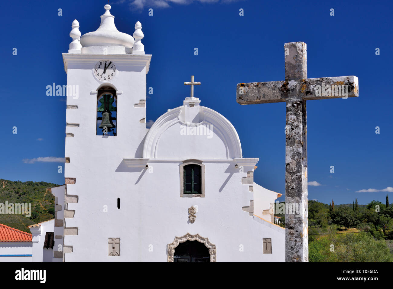 Idyllic white washed church with medieval cross in front of baby blue sunny  sky Stock Photo