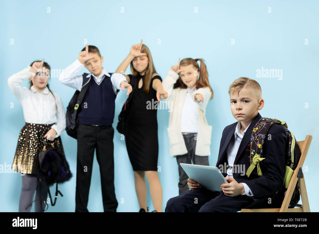 Little boy sitting alone on chair and suffering an act of bullying ...